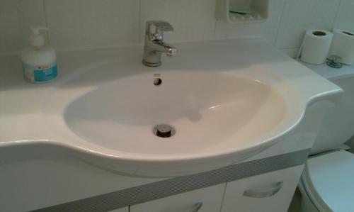 a white sink in a bathroom next to a toilet at Family Apartment in Patra