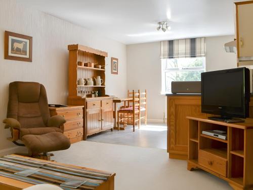 a living room with a television and a chair at Brigham Farm Apartments in Keswick