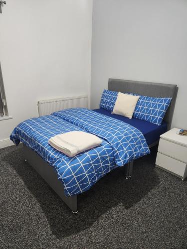 a bedroom with a bed with blue and white sheets at Manor House walsall 2 in Walsall