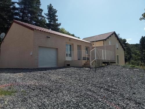 a house with a garage and a gravel driveway at Maison calme in La Bastide-Puylaurent