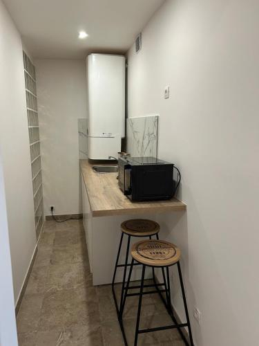 une cuisine avec deux tabourets et un four micro-ondes sur un comptoir dans l'établissement Appartement balnéothérapie avec extérieur, à Montreuil