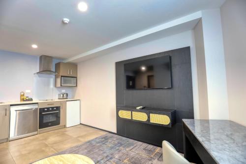 a kitchen with a counter and a tv on the wall at Marsden Suites Albany in Albany