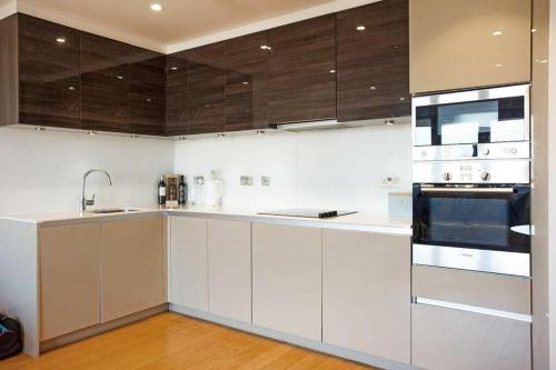 a kitchen with white appliances and wooden cabinets at Auracasa 2 Bed O2 Canning suite in London