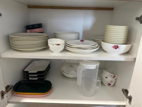 a white shelf with plates and bowls on it at B3A-5 Suites in Papar