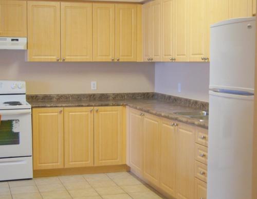 a kitchen with yellow cabinets and a white refrigerator at Hotel Laurier - Apartment Style Residence in Waterloo