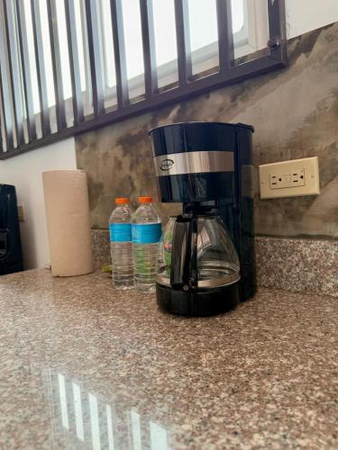 a coffee maker sitting on a counter with water bottles at La Placita - Apartamentos in Las Tablas