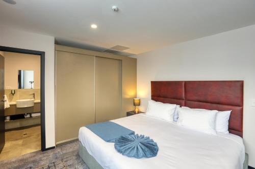 a bedroom with a large bed and a bathroom at Marsden Suites Albany in Albany