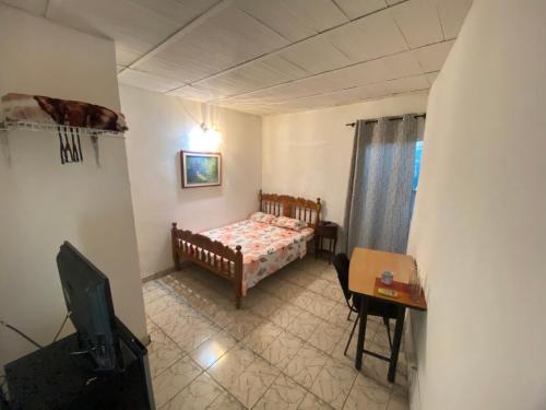 Un dormitorio con una cama, un escritorio y un televisor. en Perez Leal, en San Antonio del Táchira