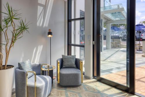 a lobby with two chairs and a table and glass doors at Marsden Suites Albany in Albany