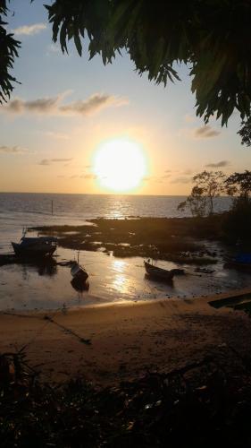 a sunset on a beach with boats on the shore at Paraíso de Deus in Colares