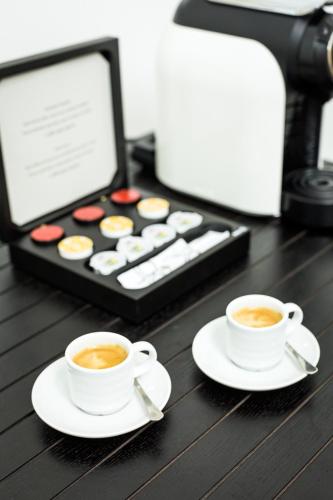 two cups of coffee sitting on a table with a box of cupcakes at Castanheiro Boutique Hotel in Funchal