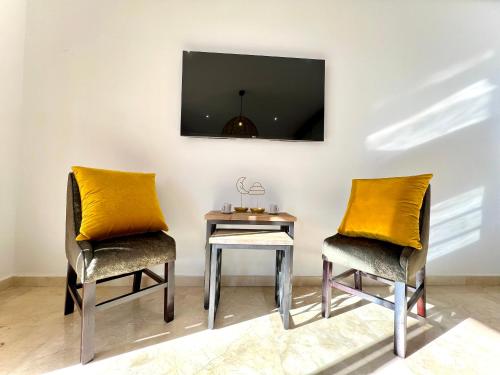 two chairs and a table with a tv on a wall at Ritz carlton luxurious stay in Marina Smir