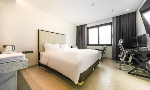 a bedroom with a large white bed and a desk at Daegu Dongseongro Hotel Labella in Daegu