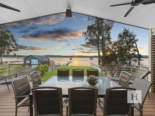 a table and chairs on a deck with a view of the water at Sunset Central Coast in Mannering Park