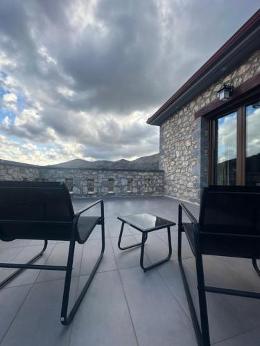 a patio with two chairs and a table on a building at Wood & Stone Guesthouse in Khrisovítsion