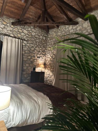 a bedroom with a white bed and a stone wall at Wood & Stone Guesthouse in Khrisovítsion