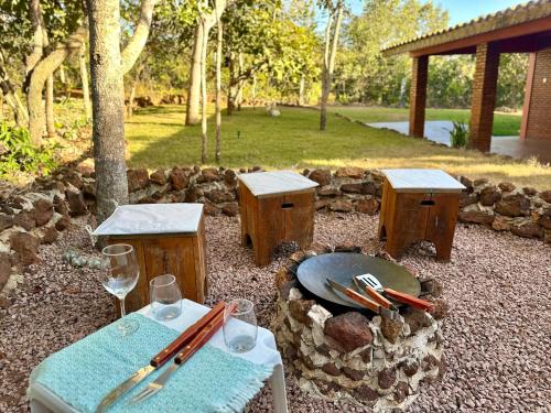 a table and benches with a plate and wine glasses at Casa para relaxar em Chapada dos Guimarães in Chapada dos Guimarães