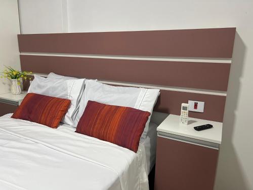 a bedroom with a bed with a brown headboard at Aconchego no Canto do Forte - Ar Condicionados - Tvs Grandes - Wi-fi e Estacionamento Incluso! in Praia Grande