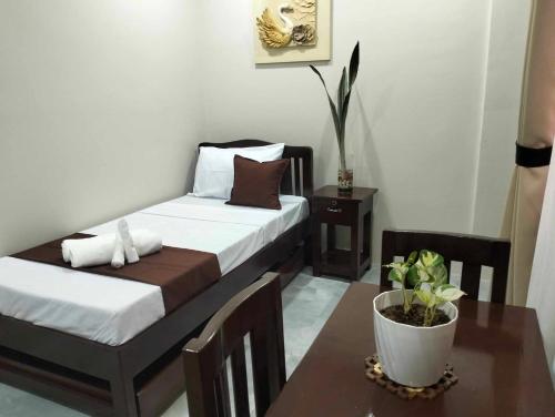 a bedroom with two beds and a table with a plant at JMorino Pension House in Puerto Princesa City