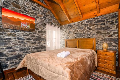a bedroom with a bed and a stone wall at King's House - Centennial House in Ribeira do Raposo