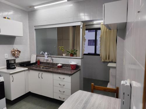 a small kitchen with a sink and a mirror at Apartamento aconchegante no centro da cidade in Serra Negra