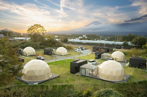 a group of domes in a field with a mountain in the background at Relam Glamping Resort Gotemba in Gotemba