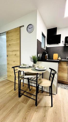 une table et des chaises dans une cuisine avec une horloge murale dans l'établissement L'écrin Bleu - Studio Cosy Intra-Muros, à Avignon