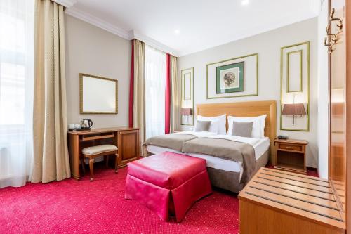 a hotel room with a large bed and a red stool at Hotel Caruso Old Town in Prague