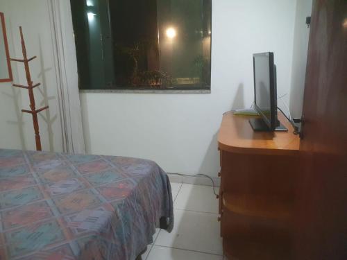a bedroom with a bed and a desk with a television on it at quarto duplo in Caraguatatuba