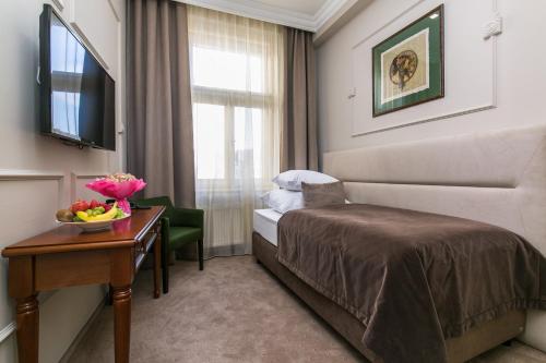 a hotel room with a bed and a table with a bowl of fruit at Hotel Caruso Old Town in Prague