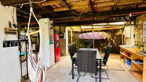 a table and chairs in a room with a surfboard at Mata Nui Eco hostel in Hanga Roa