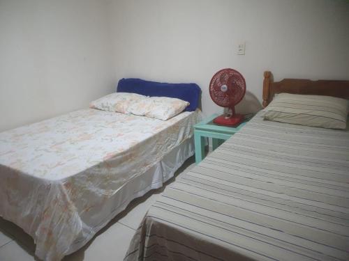 a bedroom with two beds and a table with a fan at quarto duplo in Caraguatatuba