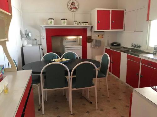 une cuisine avec des armoires rouges et une table et des chaises noires dans l'établissement Country Style Cottage, à Ouyen