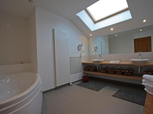 bagno con 2 lavandini, vasca e specchio di Superbe Ferme Rénovée avec Cheminée, Wifi, et Jeux Extérieurs près de Gérardmer et Épinal - FR-1-589-28 a Belmont-sur-Buttant