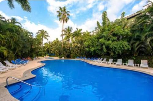 a large swimming pool with chairs and palm trees at Cozy Marbella suits 2 bed 2 bath in Puerto Vallarta