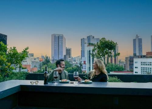 a man and woman sitting at a table with wine glasses at Loft -Skyline view- Rooftop pool, gym, bbq & more in Mexico City
