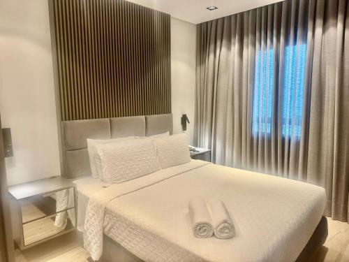 a bedroom with a white bed with two towels on it at Suites in B Tree Av Paulista in São Paulo