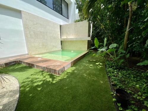 a small swimming pool in a backyard with green grass at Alexis House in Mérida