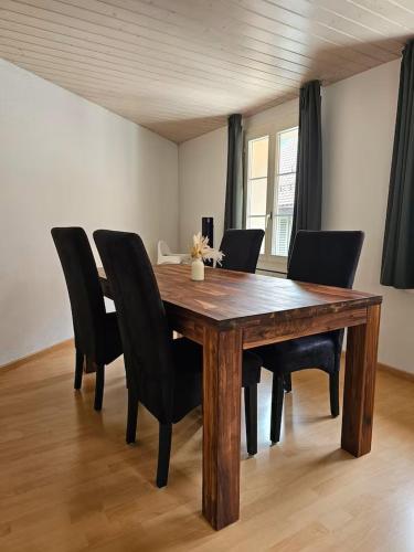 a wooden dining room table with black chairs at Perle am Vierwaldstättersee in Fluelen