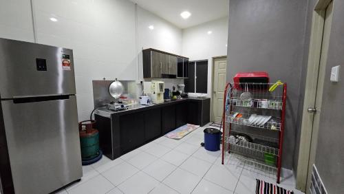 a kitchen with a counter and a refrigerator in it at Mem's Homestay Haziiq Jaya in Kuching