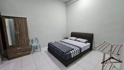 a bedroom with a bed and a chair in it at Mem's Homestay Haziiq Jaya in Kuching