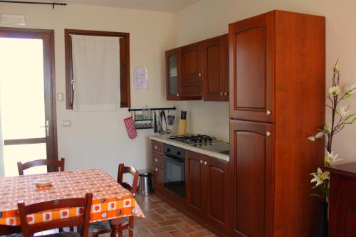 a kitchen with wooden cabinets and a table and a stove at Residenza Principina in Principina Terra