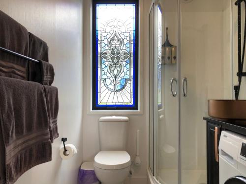 a bathroom with a toilet and a stained glass window at Luxury Farm Escape Tiny Home New Plymouth-Egmont Village in Egmont Village