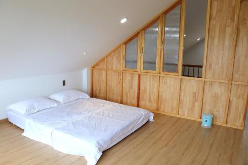 a bedroom with a white bed and wooden walls at Chiri House in Khu Chi Lăng