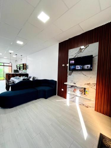 a living room with a couch and a tv on a wall at Blue house in Puerto Ayora