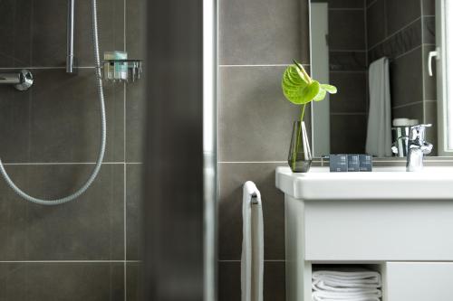a bathroom with a shower and a sink and a mirror at The Grey Design Hotel in Dortmund