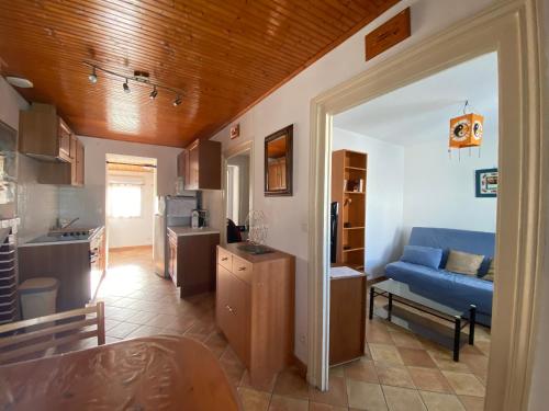 Il comprend une cuisine et un salon avec un canapé bleu. dans l'établissement Maison rénovée, proche plage et commerces, parking, jardin privé - FR-1-22-221, à La Tranche-sur-Mer