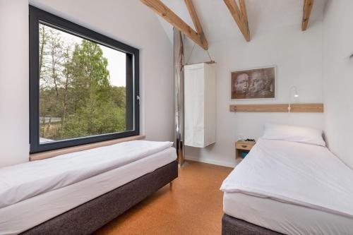 a bedroom with two beds and a large window at Holiday Home by Lake Wise ka with Sauna in Wisełka