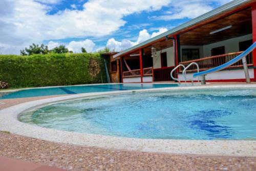 a large swimming pool in front of a house at Finca Hotel La Paloma in Quimbaya
