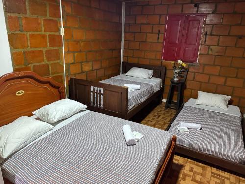 a room with two beds and a brick wall at Finca Hotel La Paloma in Quimbaya